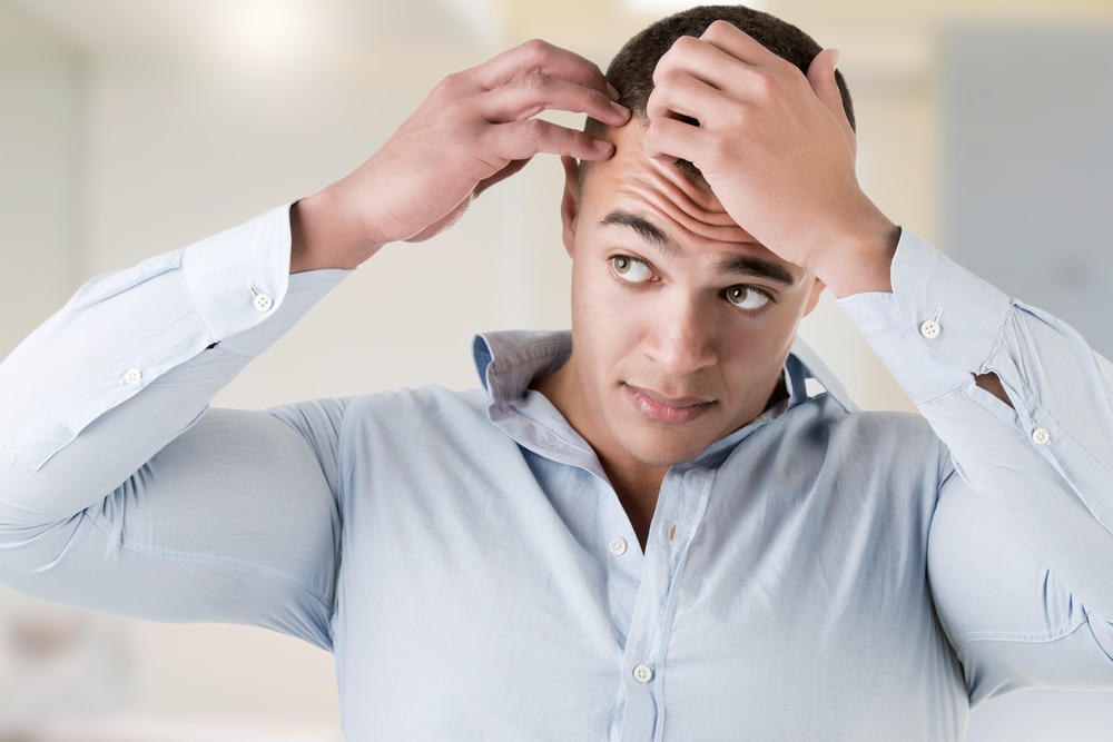 Man looking in the mirror with concern over hair loss.